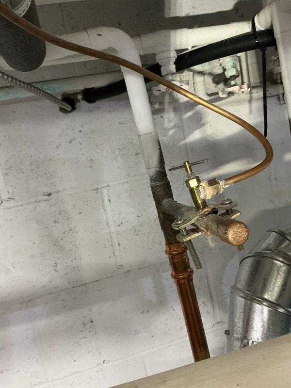 Performed annual heating tune-up on 12-year-old Lennox furnace. Documented significant corrosion and mineral buildup on valve assembly with copper piping connections. Photos taken of corroded brass valve components and mounting infrastructure for service record.