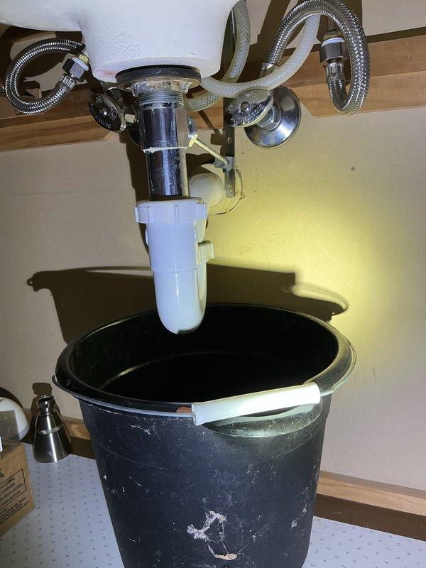 Responded to a service call for bathroom faucet issue in single-family residence. Inspected under-sink plumbing and found a leak in the P-trap assembly where chrome center pipe connects to PVC pipes. Replaced damaged P-trap components and verified proper connection of flexible supply lines, resolving the leak that homeowner had previously attempted to repair.