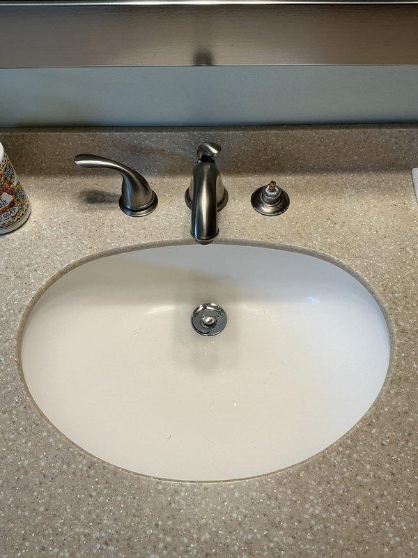 Responded to a service call for bathroom faucet issue in single-family residence. Inspected under-sink plumbing and found a leak in the P-trap assembly where chrome center pipe connects to PVC pipes. Replaced damaged P-trap components and verified proper connection of flexible supply lines, resolving the leak that homeowner had previously attempted to repair.