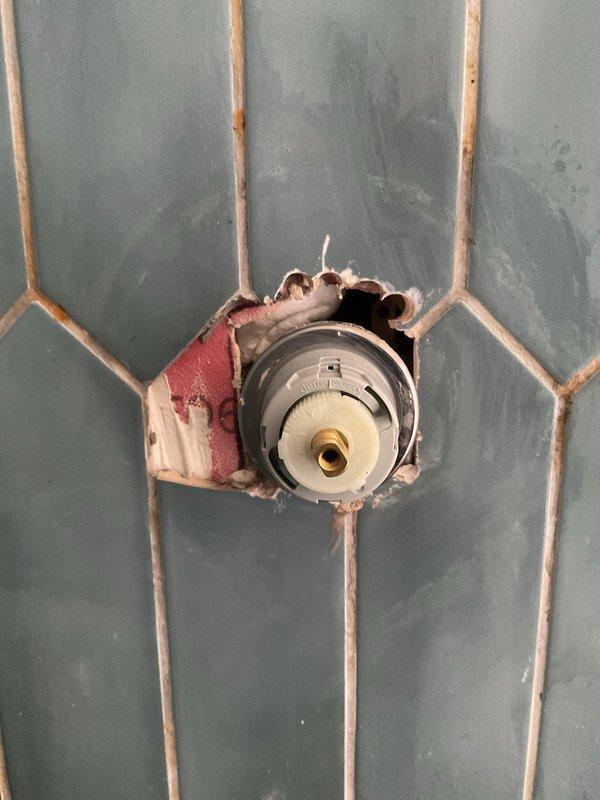 Completed quoted repair to replace shower shut off valve and cartridge. Removed damaged tile to access valve assembly, then installed new components and verified proper water flow. Finished installation with brushed nickel trim kit including single lever control handle and tub spout, restoring full functionality to the shower system.