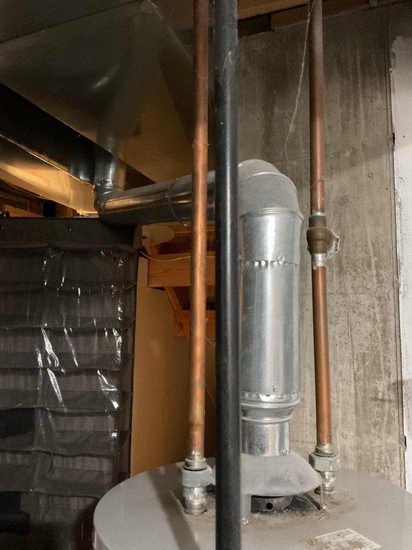 Conducted water heater replacement estimate for client's father (non-English speaking) at residence. Inspected existing water heater system, including connected copper piping, ventilation components, and current installation configuration in basement utility area. Photos documented the current unit and surrounding mechanical infrastructure for accurate quote preparation.