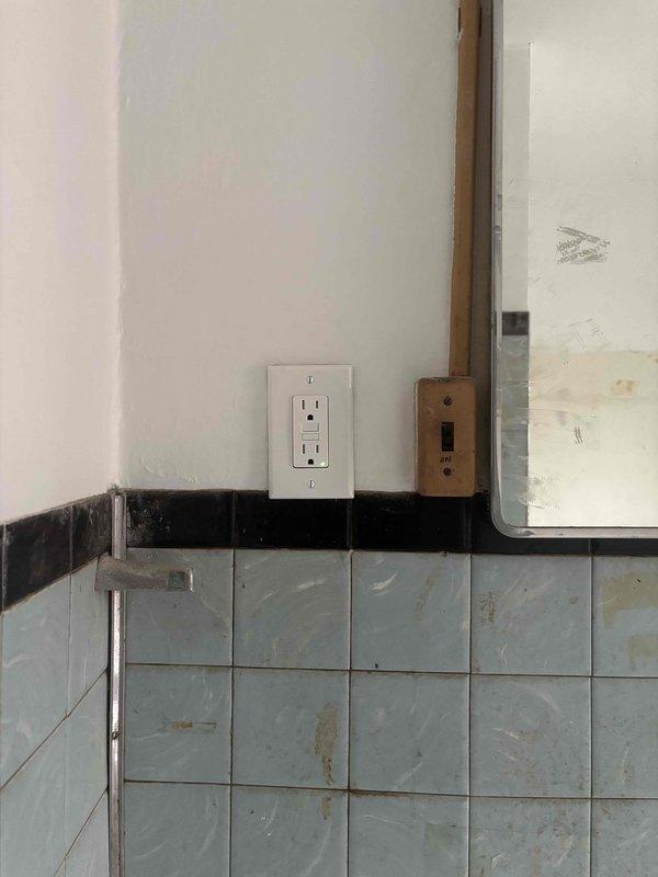 Installed new GFCI outlet in bathroom with aging tile work, replacing older electrical components while maintaining proper connections to existing wiring system. The installation enhances electrical safety in the moisture-prone area and brings the fixture up to current code requirements.