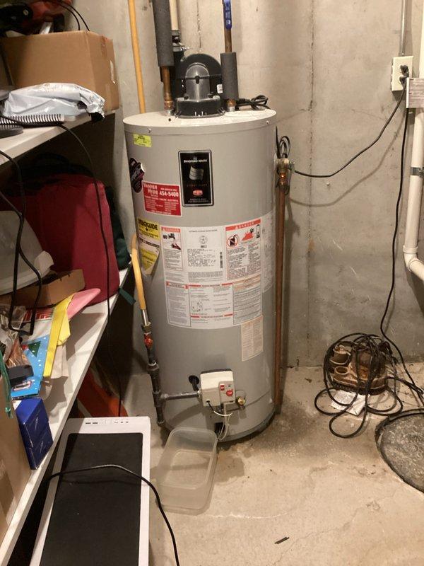Responded to emergency service call for a leaking 18-year-old Bradford water heater. Upon inspection, confirmed active leak from tank with water being collected in container below valve. Completed diagnostic assessment and provided customer with replacement options due to age of unit and tank failure.