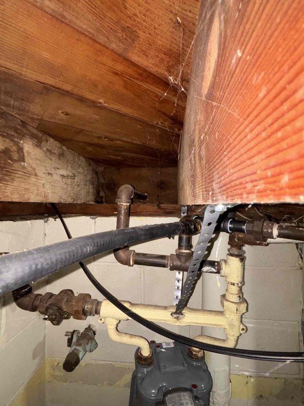 Performed gas line replacement service at a 70-year-old residence, connecting whole home generator to existing gas supply system. Inspection revealed aging infrastructure with various repairs and additions over time, including mixed piping materials (black iron and PVC components) and supporting brackets. Work included proper installation and securing of gas lines in the utility area/crawlspace, ensuring all connections were leak-free and compliant with current gas safety standards.