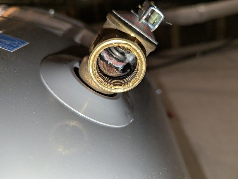 Responded to service call for a 5-year-old Rheem water heater with significant leakage from copper pipe. Diagnostic inspection revealed severe mineral buildup and corrosion at the threaded brass fitting connection, with calcified deposits extending from the connection point. Documented evidence of hard water damage contributing to the failure of the plumbing component.