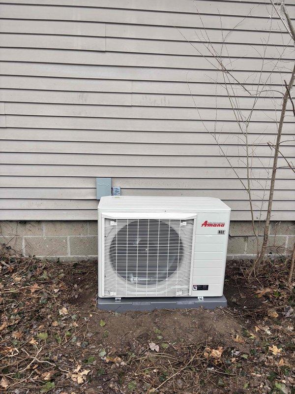 Successfully installed new Amana HVAC system including furnace with attached humidifier in utility room and outdoor condensing unit. System includes proper PVC condensate drainage, electrical connections, and all required ductwork, with the outdoor unit professionally mounted on concrete pad adjacent to home's exterior.