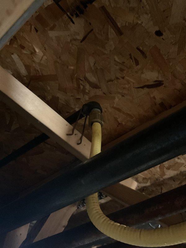 Responded to gas leak call at customer's property. Upon inspection, identified a leak in the yellow corrugated flexible gas line running through the basement ceiling joists. Repaired the compromised section of gas line, pressure tested the system to confirm resolution, and documented the repair with photographs of the installation area.