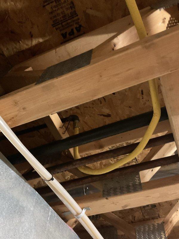 Responded to gas leak call at customer's property. Upon inspection, identified a leak in the yellow corrugated flexible gas line running through the basement ceiling joists. Repaired the compromised section of gas line, pressure tested the system to confirm resolution, and documented the repair with photographs of the installation area.