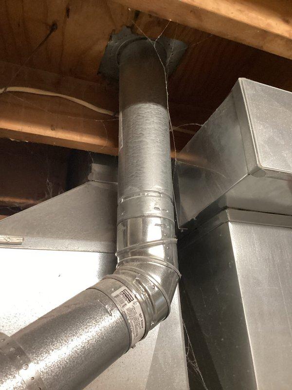 Performed inspection of 15-year-old water heater requiring replacement. Observed aging cylindrical unit with metal vent pipe showing discoloration at connection points. Documented existing installation including copper supply lines and galvanized vent system with 90-degree elbow joint venting through ceiling ductwork.