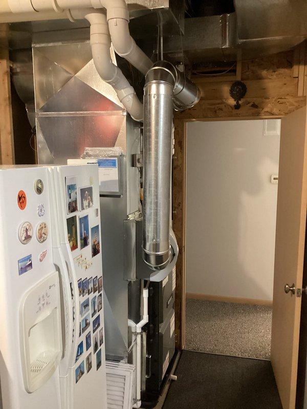 Completed installation of new furnace system with proper metal ductwork and PVC ventilation components in utility room, along with replacement of outdoor AC condenser unit which was properly mounted on gravel base with electrical disconnect box and drainage system. All connections were verified and system is operating as designed.