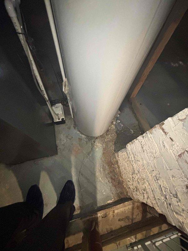 Responded to no hot water call and found aging water heater with active leak at base. Diagnosed terminal tank failure with visible corrosion and water accumulation around base. Recommended complete replacement due to age and deterioration of unit.