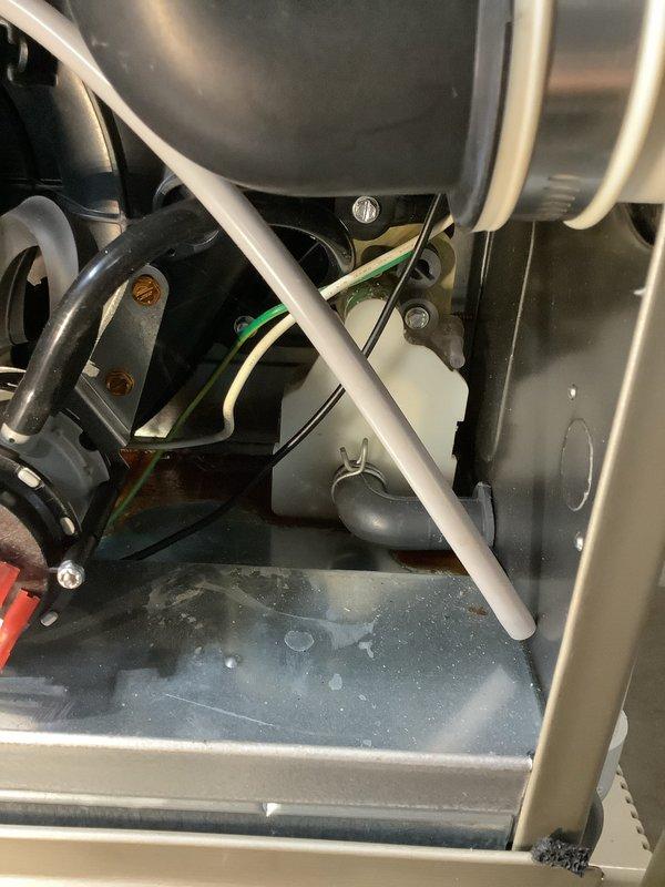 Diagnosed 2-year-old Carrier system showing red light fault code with internal leak evident. Found black fluid pooling beneath unit and moisture inside near mechanical components, indicating potential refrigerant or condensate issue requiring further investigation before system can be safely returned to operation.