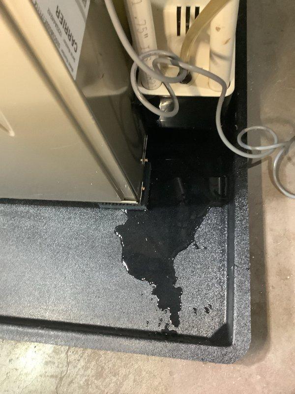 Diagnosed 2-year-old Carrier system showing red light fault code with internal leak evident. Found black fluid pooling beneath unit and moisture inside near mechanical components, indicating potential refrigerant or condensate issue requiring further investigation before system can be safely returned to operation.