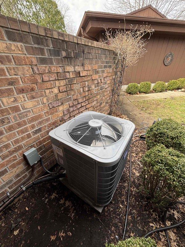 Successfully completed installation of new residential AC unit, positioning the condenser against exterior brick wall with proper electrical connections and refrigerant lines. Unit was properly situated on soil surface with adequate clearance for airflow, and all necessary paperwork was completed following installation.