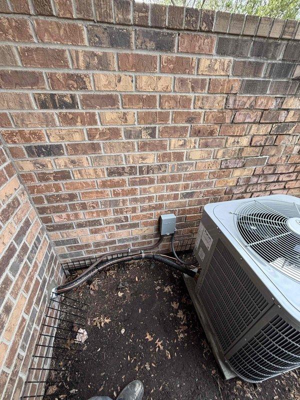 Successfully completed installation of new residential AC unit, positioning the condenser against exterior brick wall with proper electrical connections and refrigerant lines. Unit was properly situated on soil surface with adequate clearance for airflow, and all necessary paperwork was completed following installation.