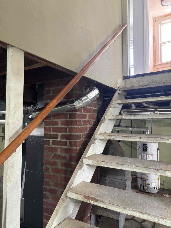 Responded to an inspector correction for a partially approved inspection. Verified the chimney liner was still in its packaging and not properly installed as required. Documented the utility area with photographs showing the installation site, including the basement mechanical room with exposed ductwork, water heater, and HVAC components where the liner should have been installed.