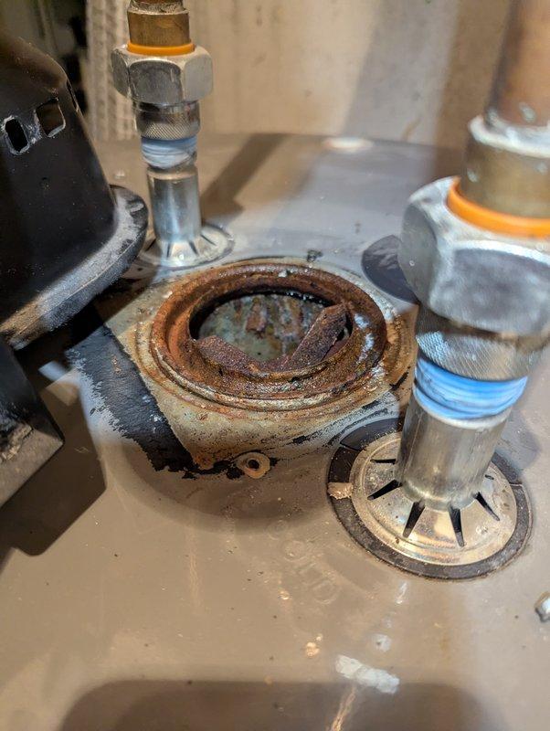 Diagnosed 13-year-old Rheem water heater that was not heating and had developed a leak, creating a puddle underneath the unit. Inspection revealed extensive corrosion and rust at the drain assembly, indicating tank failure. Recommended complete replacement of the water heater due to age and deteriorated condition.