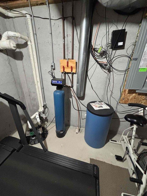 # PRWQ-Water Quality Problem Service Report

Successfully installed under-sink water filtration system per client's scheduled appointment. Mounted filtration unit beneath kitchen sink with secure connections to existing cold water supply line using braided stainless steel flex lines and brass compression fittings. System includes single-stage filter cartridge housed in blue cylindrical canister with black mounting bracket. Verified proper water flow, tested for leaks at all connection points, and confirmed filtration system operational. Existing whole-house water treatment equipment (dual-tank softener/filtration system with digital control head) remains in service in basement utility area. Documented installation with photos showing completed under-sink filter assembly and existing basement water treatment infrastructure. All work completed to plumbing code standards with no issues reported.