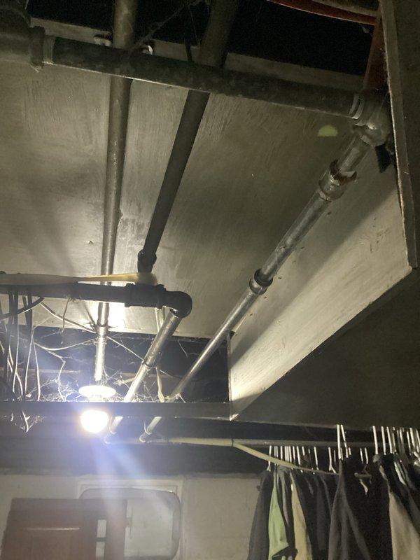 # Service Report: Plumbing Leak Problem

Responded to service call for exposed cast iron drain stack in bathroom with existing access holes from previous inspection. Customer declined full stack replacement and requested evaluation for epoxy pipe lining as alternative repair solution. Documented existing conditions including exposed horizontal drain lines and stack configuration in basement/crawl space area. Identified active leak in smaller drain lines requiring repair. Photographed pipe layout, mounting brackets, and structural access points to assess feasibility of trenchless lining installation versus traditional replacement methods.