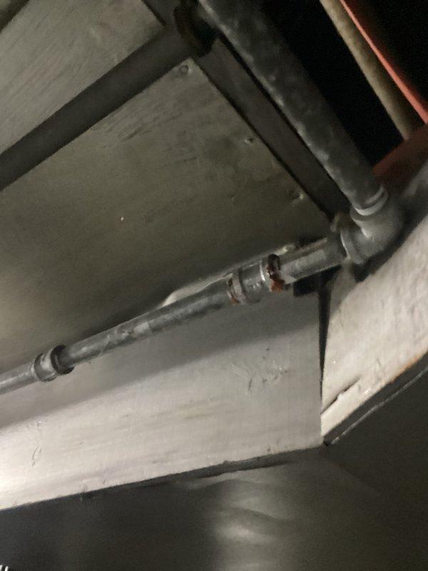 # Service Report: Plumbing Leak Problem

Responded to service call for exposed cast iron drain stack in bathroom with existing access holes from previous inspection. Customer declined full stack replacement and requested evaluation for epoxy pipe lining as alternative repair solution. Documented existing conditions including exposed horizontal drain lines and stack configuration in basement/crawl space area. Identified active leak in smaller drain lines requiring repair. Photographed pipe layout, mounting brackets, and structural access points to assess feasibility of trenchless lining installation versus traditional replacement methods.