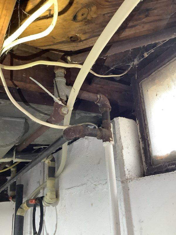 # Service Report: Garbage Disposal Repair

Responded to service call for non-operational garbage disposal unit. Upon arrival, inspected kitchen sink area and identified disposal system beneath sink with dark green granite countertop. Accessed disposal unit from basement crawl space to assess mechanical and electrical components. Examined disposal mounting assembly, drain connections, and associated plumbing infrastructure including corroded supply lines and drainage pipes. Diagnosed failure point in disposal system and performed necessary repairs to restore unit to proper working condition. Tested disposal operation to verify functionality and confirmed proper drainage with no leaks at connection points. Unit now operating normally with adequate grinding performance and proper waste discharge.