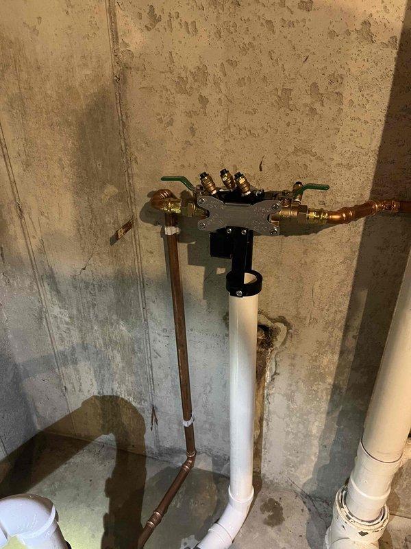 # Job Description

Responded to a sump pump and water backup emergency under a QUOTR-quoted repair authorization. Upon arrival, assessed the existing plumbing system and identified failures in the backup prevention infrastructure that were allowing water intrusion during heavy flow conditions.

Installed a comprehensive water backup prevention system consisting of dual check valve assemblies with brass fittings and shut-off valves on the main water supply line. Mounted a white filtration housing unit to the concrete wall using secure black brackets, integrating it with the existing copper supply piping. Connected all components using appropriate brass compression fittings and copper pipe extensions to ensure proper water flow and system isolation capability.

On the drainage side, configured a white PVC pipe assembly in a vertical loop configuration to manage sump discharge and prevent backflow. Integrated two electronic water backup prevention devices with American-flag-branded housin