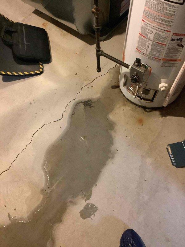 # Water Heater Problem Service Report

Responded to service call for 13-year-old gas tank water heater experiencing strange noises and active water leakage. Upon arrival, found significant water accumulation on basement floor surrounding unit, confirming active leak from aging water heater. Documented extensive water damage on concrete surface with multiple photographs showing puddle spread and equipment condition. Assessed water heater specifications and plumbing connections, noting copper piping and brass fittings at top of unit. Evaluated overall system condition consistent with unit age of 11-15 years and typical end-of-service-life failure patterns. Provided new homeowner with documentation of current equipment status and leak severity for insurance and replacement planning purposes.