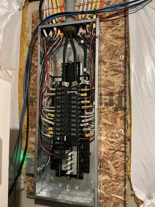 # Electrical Estimate Summary

Completed on-site electrical estimate for portable generator integration and associated wiring requirements. Evaluated existing residential electrical panel configuration, circuit distribution, and available capacity to accommodate generator transfer switch installation. Documented current panel layout showing dual-column breaker arrangement with labeled circuits for kitchen, laundry, bedrooms, and other essential loads. Assessed wire routing pathways, structural access points through OSB sheathing and stud framing, and coordination requirements with existing plumbing and mechanical systems in unfinished interior space to develop comprehensive scope and material requirements for generator connection project.