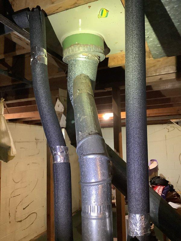 # Service Report: Water Heater Estimate

Completed comprehensive water heater evaluation for residential property. Existing Whirlpool tank-type water heater exhibits significant deterioration including extensive rust staining on exterior casing, severe corrosion at top fittings and valve connections, and visible water damage patterns indicating potential internal tank failure or chronic leakage from upper components. Unit displays advanced age-related wear compromising structural integrity and operational reliability.

Assessed existing plumbing infrastructure including supply lines, discharge piping, and overhead connections. Documented copper supply piping with foam insulation, ceiling-mounted expansion tank assembly with pressure relief components, and current venting configuration. Evaluated installation space constraints, utility connections, and code compliance requirements for replacement options.

Provided detailed estimate comparing conventional tank-type water heater replacem