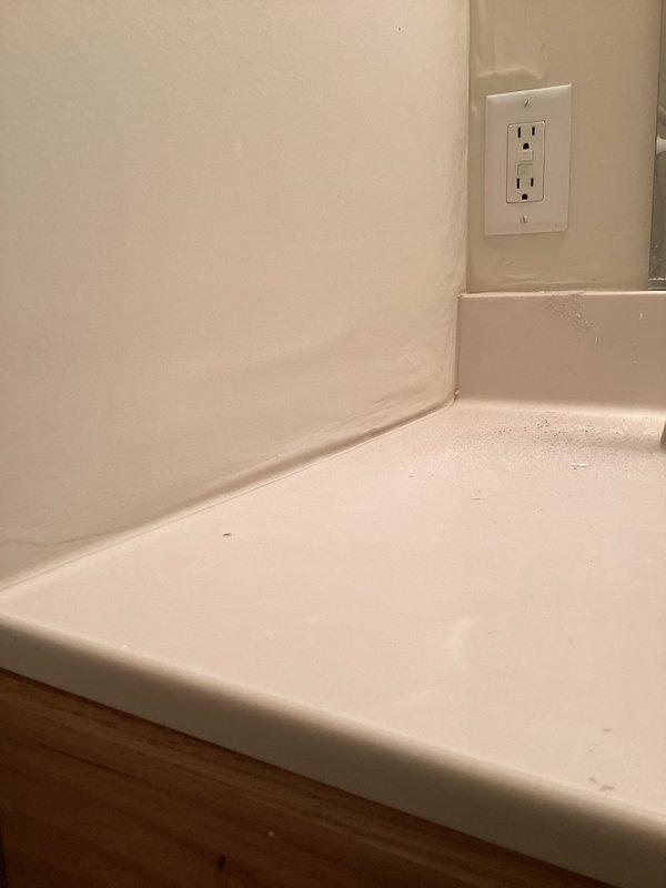 # Service Report: Plumbing Leak Investigation

Responded to emergency plumbing leak affecting multiple areas of residence, originating from recently installed tub shower assembly. Customer reported water infiltration into basement level with moisture migration through wall cavities across dwelling. Upon arrival, conducted comprehensive visual inspection of affected areas and traced leak source to shower installation completed one month prior.

Investigation revealed active water intrusion requiring immediate access to concealed plumbing connections. Created strategic access opening in wall near ceiling level to expose supply lines and drain assembly behind shower fixture. Inspection of exposed framing and plumbing infrastructure identified compromised connection point allowing water to travel through wall cavities and floor joists to lower level.

Documented existing conditions through photographic evidence showing extent of water damage to finished surfaces including countertop areas,