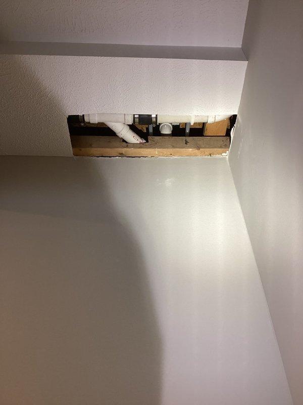 # Service Report: Plumbing Leak Investigation

Responded to emergency plumbing leak affecting multiple areas of residence, originating from recently installed tub shower assembly. Customer reported water infiltration into basement level with moisture migration through wall cavities across dwelling. Upon arrival, conducted comprehensive visual inspection of affected areas and traced leak source to shower installation completed one month prior.

Investigation revealed active water intrusion requiring immediate access to concealed plumbing connections. Created strategic access opening in wall near ceiling level to expose supply lines and drain assembly behind shower fixture. Inspection of exposed framing and plumbing infrastructure identified compromised connection point allowing water to travel through wall cavities and floor joists to lower level.

Documented existing conditions through photographic evidence showing extent of water damage to finished surfaces including countertop areas,