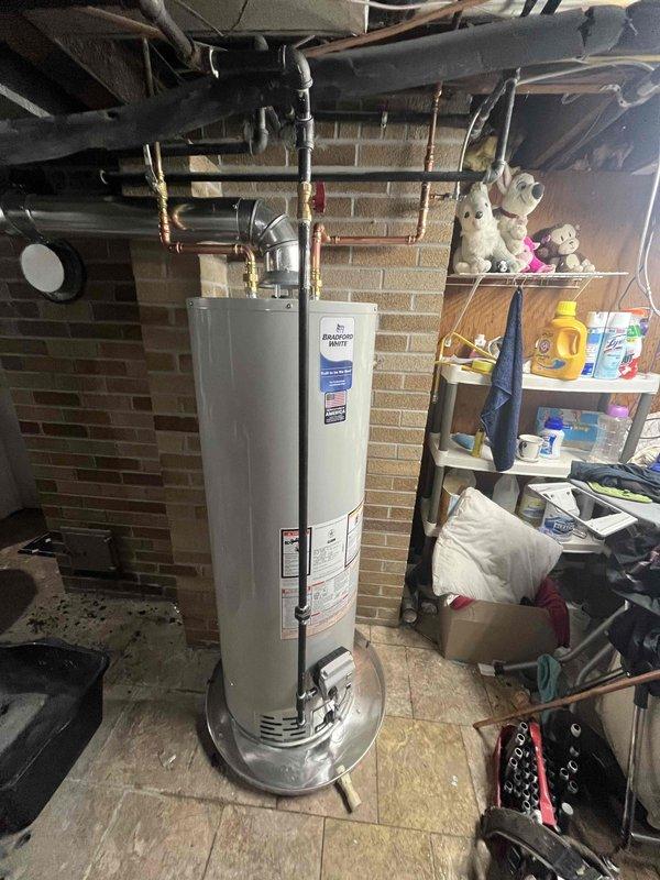 # Water Heater Installation Summary

Successfully completed the installation of a 40-gallon natural gas water heater in the customer's basement utility area. The new unit was positioned on the existing tiled floor space, with all necessary connections made to the overhead piping system, including gas supply lines, water supply and discharge lines, and proper venting through the metallic ductwork system that extends through the brick wall. All installations were completed in accordance with manufacturer specifications and local building codes, with the unit fully operational and tested for proper function upon completion.