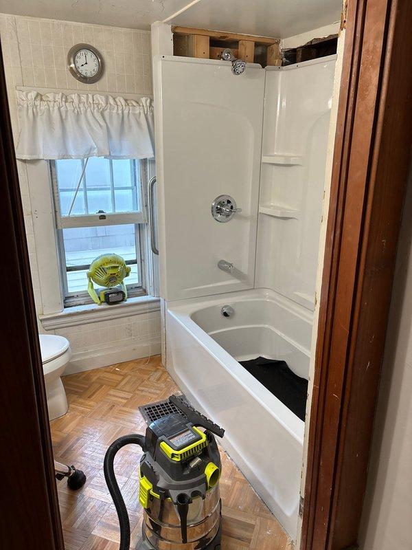 # Plumbing Project Install - Tub/Shower with Surround

Completed full installation of tub/shower combination unit with integrated wall surround system. Removed existing bathing fixtures and prepared rough-in plumbing connections for new installation. Set and leveled acrylic bathtub unit, ensuring proper drain alignment and secure anchoring to wall studs.

Installed three-piece shower surround wall panels with integrated corner shelving units, sealing all seams and joints with waterproof adhesive and caulking to prevent moisture intrusion. Mounted chrome shower valve trim kit and coordinating showerhead assembly to wall panels per manufacturer specifications. Connected supply lines to mixing valve and verified proper hot/cold water operation and temperature control.

Performed final pressure testing of all connections to confirm leak-free installation. Completed finish caulking around tub perimeter and wall panel seams. Cleaned work area and removed all debris and packaging materials. S