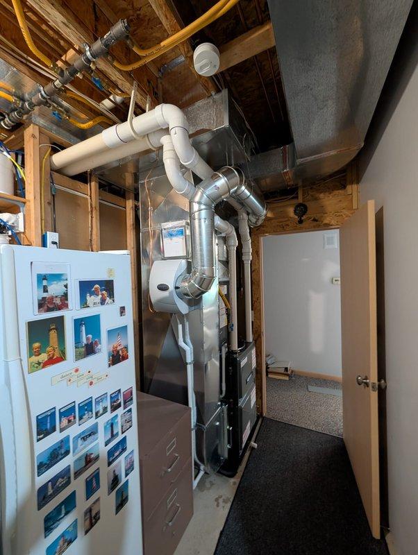 Relocated humidifier unit and associated MC cable in residential mechanical space to optimize system layout and accessibility. Rerouted electrical connections and repositioned equipment while maintaining proper clearances from furnace, ductwork, and gas lines in basement utility area.