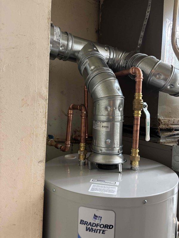 Completed installation of a 40-gallon tall natural gas Bradford White water heater in residential utility closet. Configured all copper supply line connections, gas line hookup, and venting ductwork to manufacturer specifications. Unit installed adjacent to existing HVAC system with proper clearances maintained and all connections tested for safe operation.