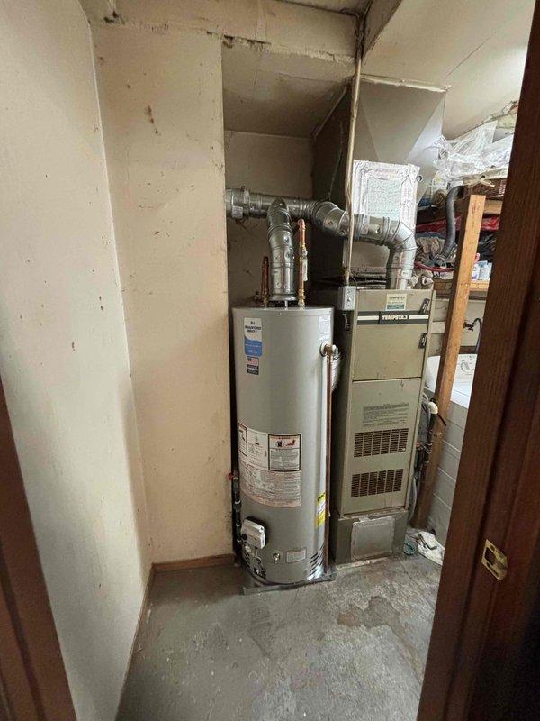 Completed installation of a 40-gallon tall natural gas Bradford White water heater in residential utility closet. Configured all copper supply line connections, gas line hookup, and venting ductwork to manufacturer specifications. Unit installed adjacent to existing HVAC system with proper clearances maintained and all connections tested for safe operation.