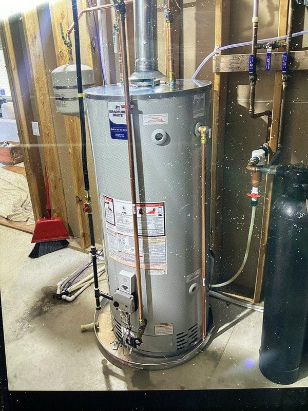 Completed full water heater replacement installation in residential utility space. Removed existing unit and installed new automatic storage water heater with proper venting system, including metal exhaust vent pipe routed from top of unit. Connected all copper supply lines, installed PEX flexible tubing connections, and mounted shut-off valves with blue handles on dedicated panel board for easy access and system control. Verified all plumbing connections for proper seal and tested unit operation to ensure safe and efficient functionality. Installation completed per manufacturer specifications with all required safety labels and compliance markings in place.