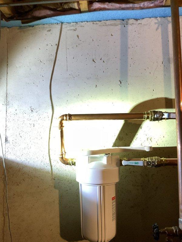 Completed installation of customer-supplied water heater with chimney liner venting system in basement utility area. Installed whole-home sediment filtration system with copper piping, brass shut-off valves, and pressure monitoring components mounted to basement wall with proper inlet/outlet configuration. Installed two tub/shower trim kits to complete bathroom fixture assemblies. All plumbing connections tested and verified operational with no leaks detected. Customer pre-paid for services, and installation was completed within one-day timeframe as scheduled.