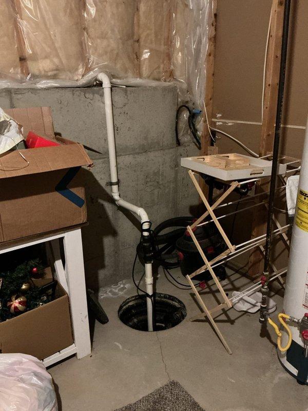 Responded to service call for sump pump drainage pipe leak and water hammer issues affecting multiple fixtures. Upon inspection, identified minor leak in sump pump discharge line where audible dripping occurred during pump cycling. Assessed plumbing system including kitchen sink, dishwasher, and shower connections experiencing aggressive water hammer. Evaluated basement utility area containing sump pump assembly with white PVC discharge piping, water treatment equipment including water softener and pressure tank, and copper supply line distribution system. Documented existing conditions of plumbing infrastructure and mechanical systems for further corrective action recommendations.