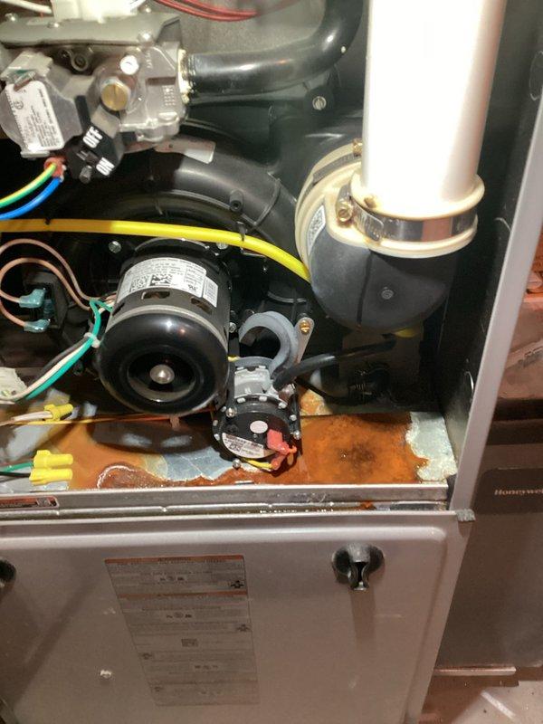 Completed annual heating maintenance on ICP furnace system. Performed comprehensive tune-up including inspection of blower motor assembly, gas valve operation, and burner components. Documented existing corrosion and rust staining in condensate pan area, though unit currently operating within normal parameters. Inspected all electrical connections, exhaust/intake piping, and verified proper motor function. Removed and photographed worn mechanical linkage component showing signs of age and wear on gear teeth assembly. All safety controls tested and confirmed operational. System cleared for continued service with recommendation to monitor condensate pan condition for potential future replacement due to observed deterioration.