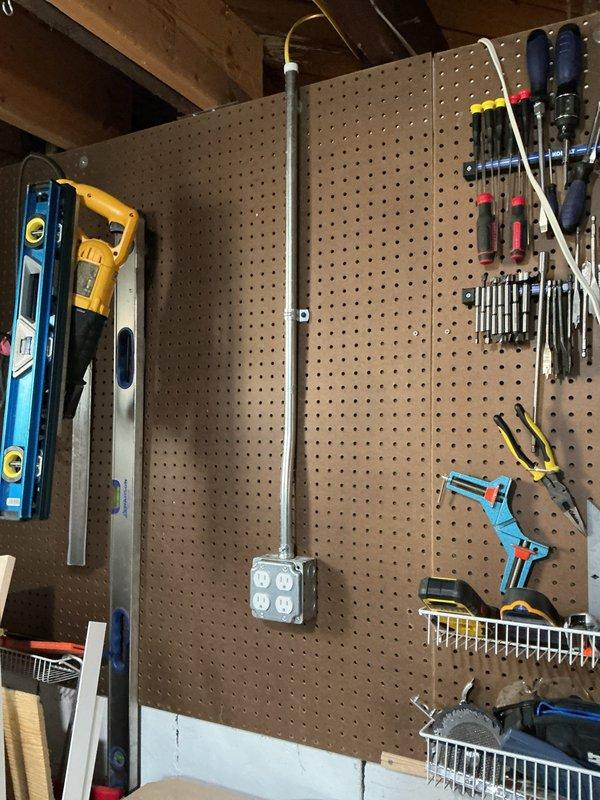 Completed three hours of general repairs in unfinished basement area, including electrical conduit work and outlet installation along beige wall surface. Organized workshop pegboard tool storage system with proper mounting and arrangement of power tools, hand tools, levels, screwdrivers, and wrenches for optimal accessibility.