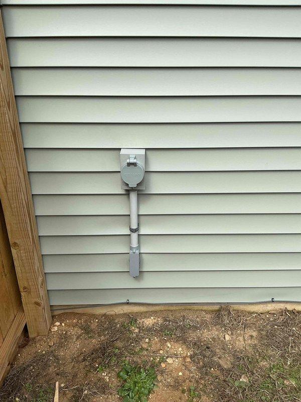 Completed installation of electrical interlock kit on residential service panel. Installed interlock device between existing meter base and electrical disconnect panel, connecting components with white PVC conduit and appropriate mounting hardware secured to vinyl siding. System now allows for safe generator connection with proper load transfer functionality.