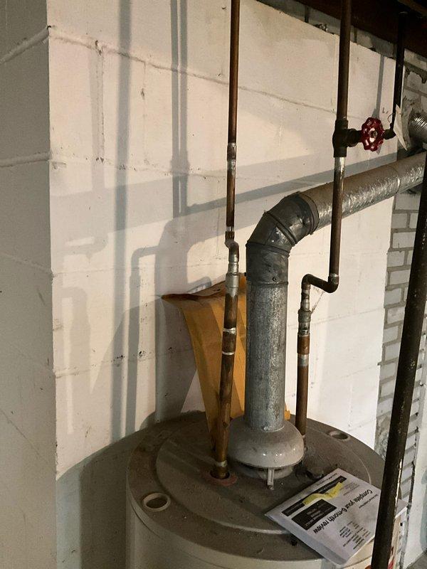 Provided estimate for water heater replacement in residential basement utility room. Evaluated existing A.O. Smith ProMax water heater installation, documented current plumbing connections including galvanized venting system with elbow joint configuration, assessed condition of concrete floor showing moisture staining around base of unit, and photographed all equipment specifications and surrounding utility infrastructure to prepare comprehensive replacement proposal.
