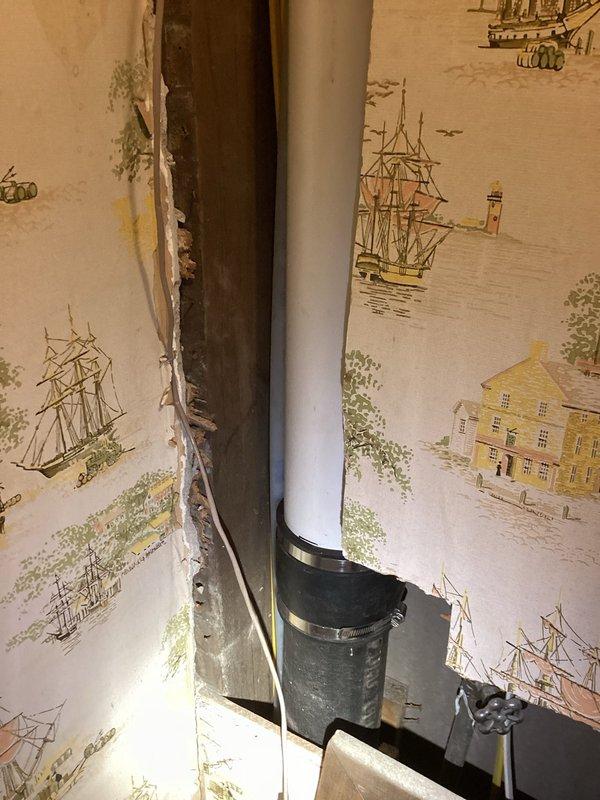 Completed partial drain repipe replacement as quoted. Accessed existing vertical drainage system through interior wall cavity, requiring removal of wall covering material to expose plumbing infrastructure. Replaced deteriorated drain piping with new white PVC drainage pipe, securing installation with proper mounting brackets at code-compliant intervals along vertical run. Pipe extends from upper floor drainage connection down through wall cavity to lower level tie-in point. All connections properly fitted and secured. Work performed in occupied residence with minimal disruption to living space. Installation meets current plumbing code requirements for residential drainage systems.