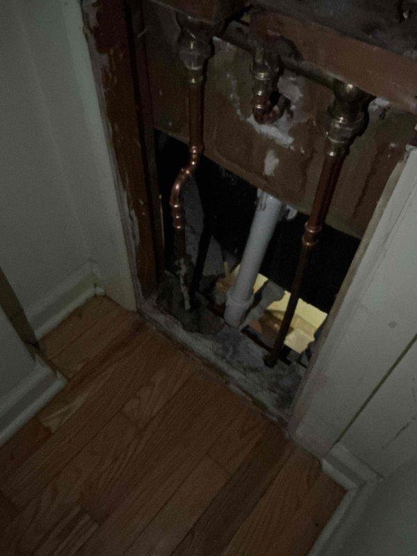 Responded to emergency callback for leaking pipe from previous day's installation. Upon arrival, accessed plumbing system through existing wall opening and identified leak at copper pipe joint fitting. Repaired faulty connection, pressure tested system to verify proper seal, and cleaned work area as requested. Documented repairs with photos showing exposed copper and PVC plumbing infrastructure within wall cavity before closing access point.