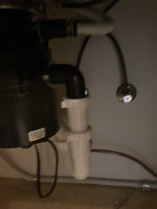 Installed new garbage disposal unit under kitchen sink with complete drain assembly replacement. Connected disposal to existing electrical outlet and integrated dishwasher drain line into system. Configured white PVC P-trap assembly to ensure proper drainage and venting. All plumbing connections secured and tested for leaks, with disposal unit properly mounted to sink basin using standard mounting hardware.