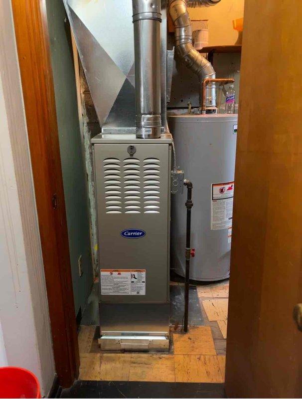 Completed full furnace replacement in residential basement utility area. Removed existing heating unit and installed new Carrier brand furnace with proper clearances and ventilation connections. Connected metallic exhaust pipe vertically to existing ductwork system. Installed curved elbow joint with metal ductwork featuring proper coupling connections to integrate with home's HVAC distribution system. Verified all duct connections are secure and sealed. Confirmed adequate spacing around furnace and adjacent water heater per code requirements. Tested unit operation and airflow through system. Collected payment as authorized.