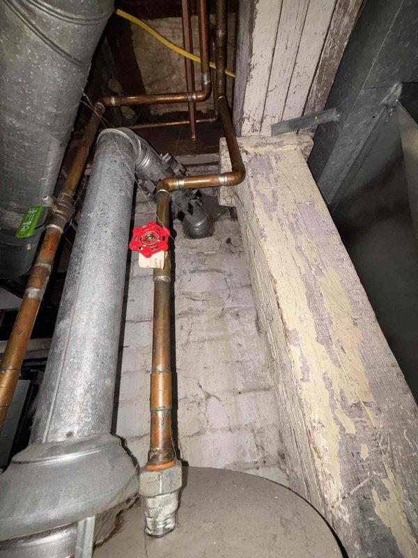 Responded to complaint of popping and banging noises from Bradford water heater (circa 2011). Upon inspection, unit was still producing hot water but exhibited signs of sediment accumulation causing the reported sounds. Documented existing plumbing configuration including copper supply lines, shutoff valves, and HVAC ductwork in utility area. Photographed water heater installation and surrounding mechanical systems for service records. Unit remains operational with continued hot water production despite acoustic issues typical of mineral buildup in aging tank.