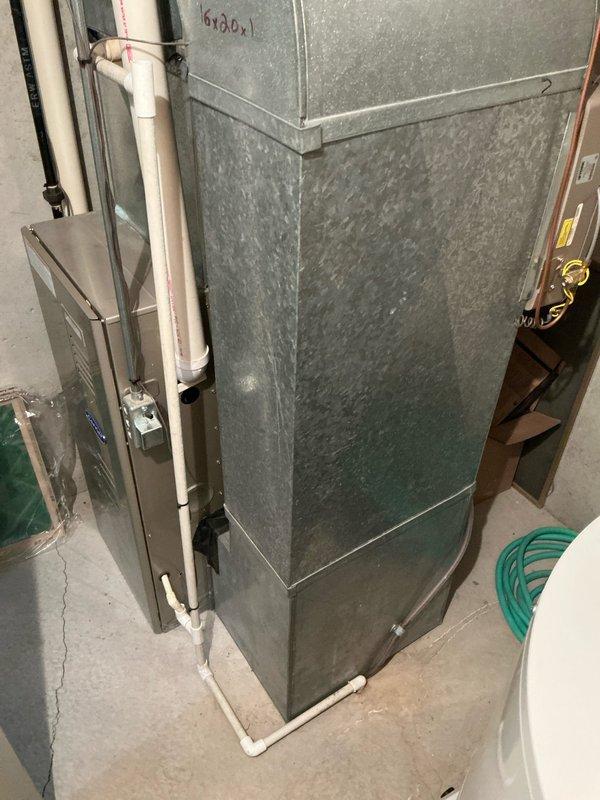 Conducted sales estimate for complete furnace replacement system. Evaluated existing HVAC installation in basement mechanical room, including current galvanized metal furnace/air handler unit with associated white PVC condensate drain lines and control components. Assessed exterior condensing unit positioned on concrete pad with connecting refrigerant lines and electrical service. Documented old discarded blower assembly and heating equipment components present on property exterior. Photographed current system configuration, clearances, ductwork connections, and existing PVC venting arrangement on building exterior. Provided comprehensive replacement options and equipment recommendations based on observed installation conditions and space constraints in utility area.