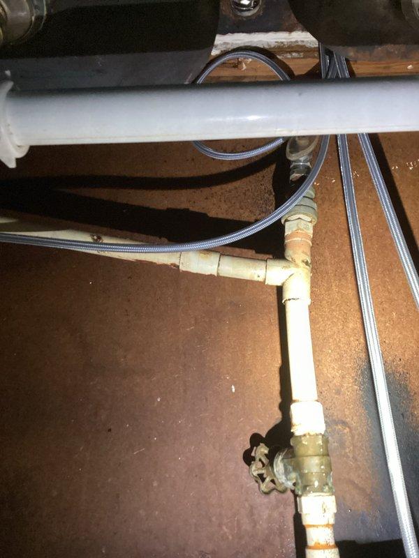 Responded to kitchen sink leak in 1959-built home. Upon inspection, found deteriorated supply line connections and aging plumbing components beneath sink cabinet. Replaced compromised supply lines with new braided stainless steel flex hoses, installed new shutoff valve with brass fittings, and updated worn pipe connections. Removed old discolored copper and brass sections showing significant patina and corrosion. Verified all connections for proper seal, tested system under pressure, and confirmed leak resolution with no active dripping or moisture present.